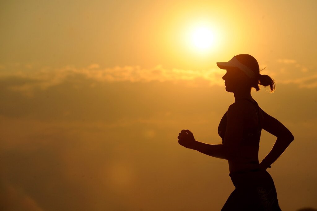 Chica corriendo con sol de fondo